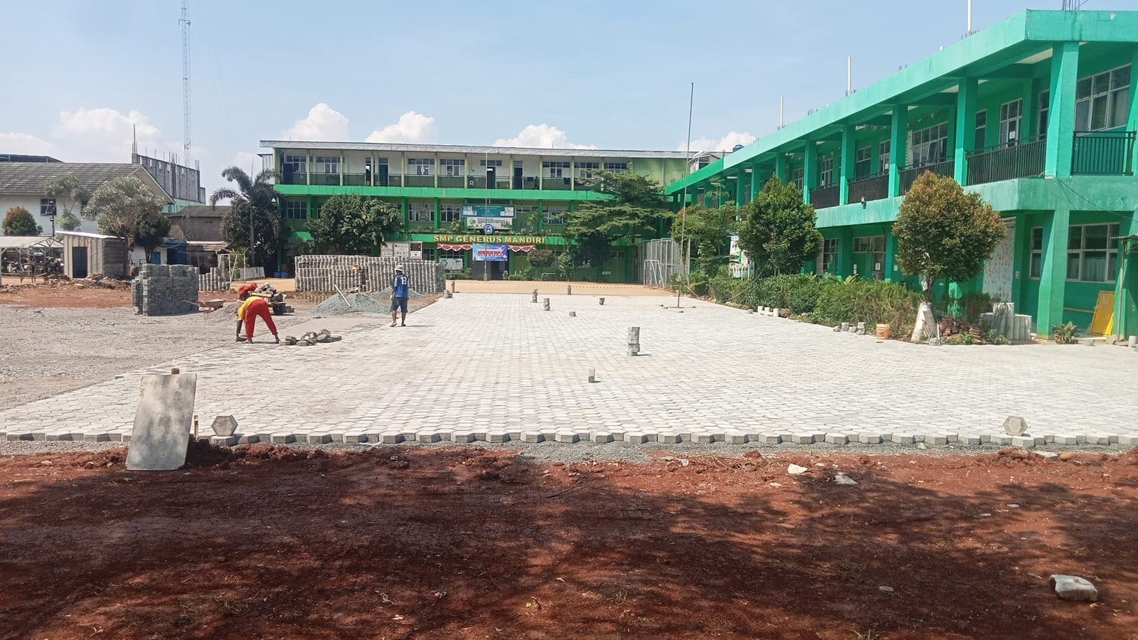 Tim mengerjakan pemasangan paving pada halaman sekolah